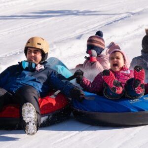 a young boy riding a snow tube down a snow covered slope